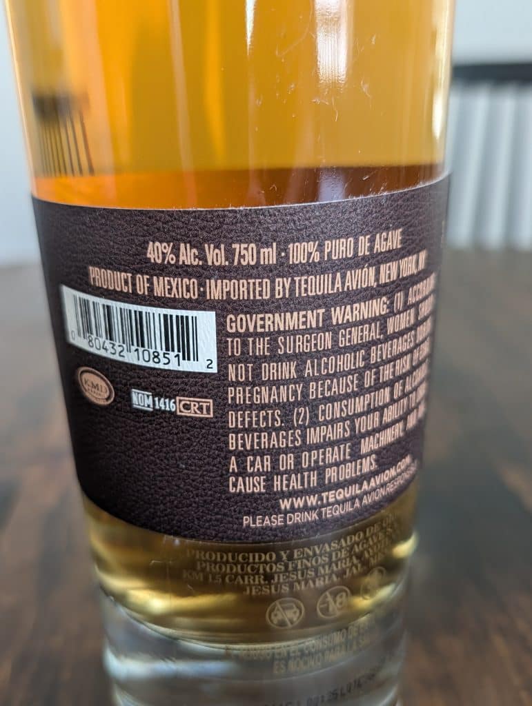 Avi&oacute;n Reserva 44 back label showing NOM 1416 beside the CRT mark, with Productos Finos de Agave and the Jes&uacute;s Mar&iacute;a address printed on the glass below